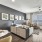 Spacious and well lit living room with wood flooring, large windows and open access to the kitchen