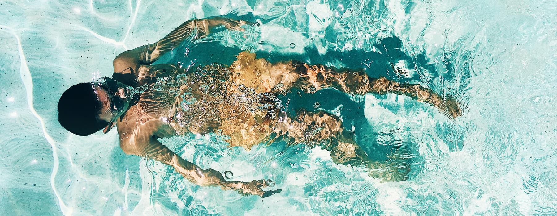 lifestyle image of a man swimming beneath the waters